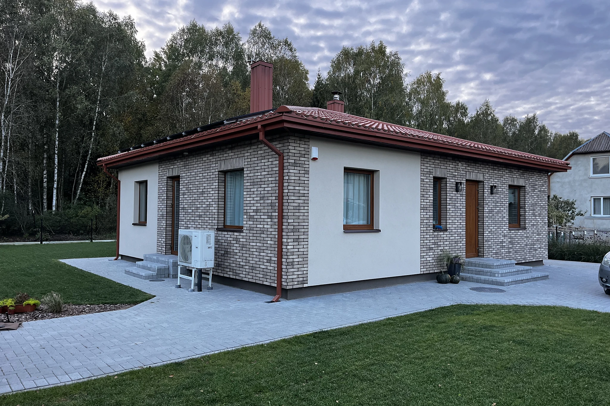 Vienaukštis namas su mūro ir tinko fasadu, trinkelių taku ir sutvarkyta veja